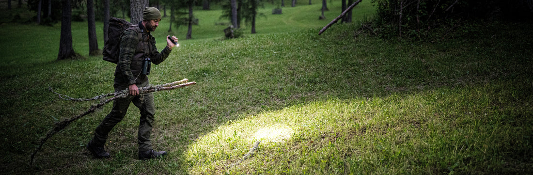 Hunter assessing ground for animal signs using a handheld TAC flashlight  