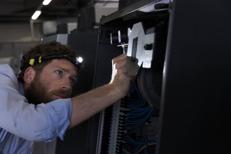 Tradesman using Ledlenser iH8R rechargeable headlamp with branded headband in Black /Yellow to light his work area