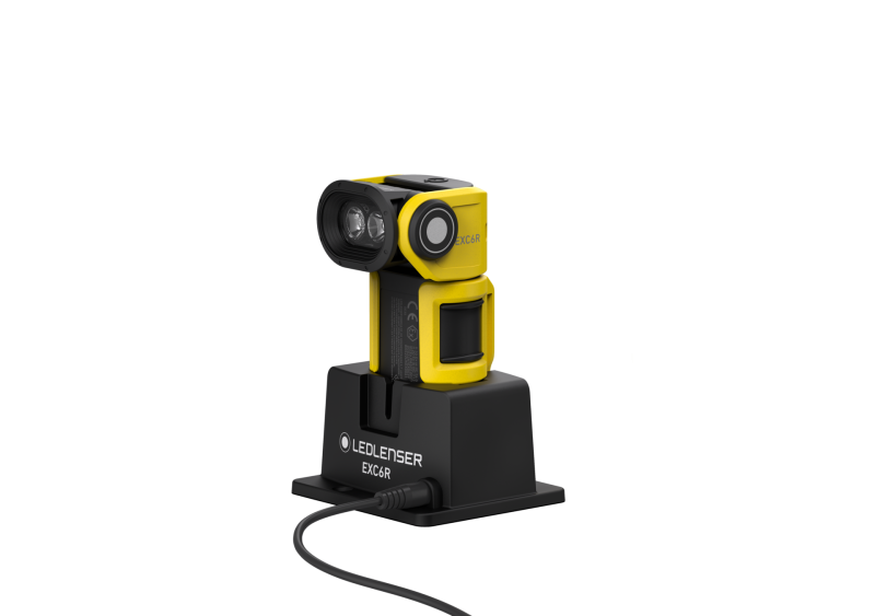 Three quarter front view of the ultra-compact, yellow and black Ledlenser EXC6R rechargeable torch shown sitting on charging station. 