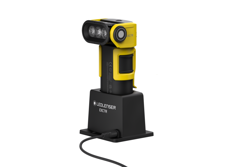 Three quarter front view of the ultra-compact, yellow and black Ledlenser EXC7R rechargeable torch. Shown in charger with charger plugged in