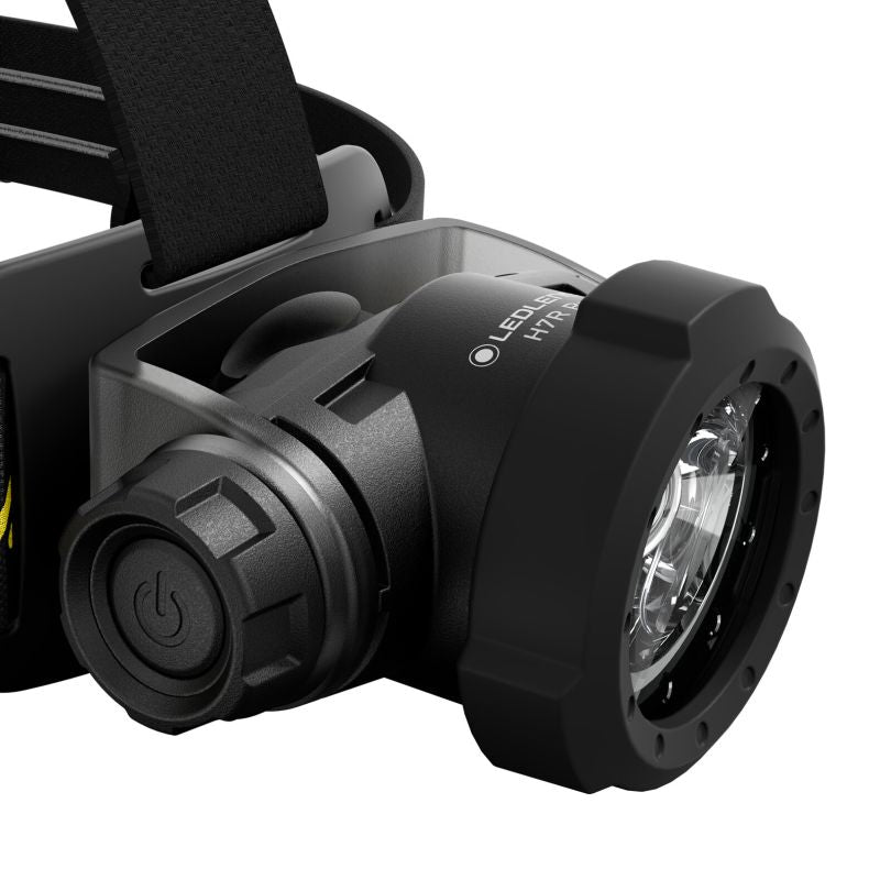 Close-up of a black Ledlenser H7R Pro headlamp with a textured adjustment knob, a black adjustable strap, and a clear lens on a white background.