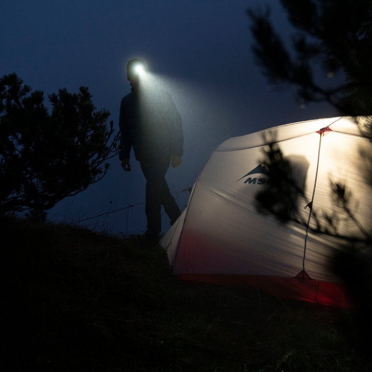 Person wearing the Ledlenser MH3 Headlamp while walking about a campsite