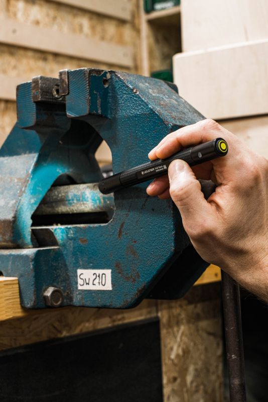 Person using a Ledlenser P4R work torch to highlight the interior of a bench vice
