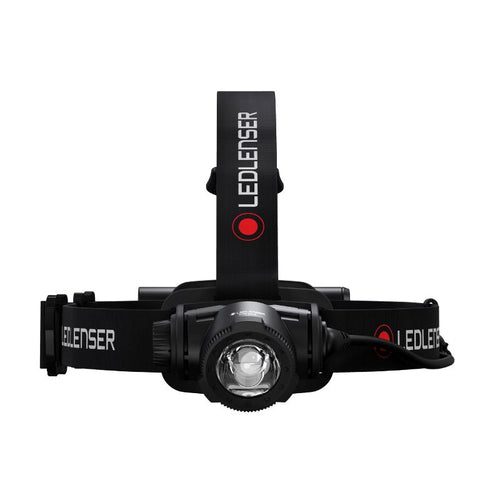 Front view of Ledlenser H7R Core rechargeable headlamp with red/black branded overhead strap and battery pack on back - Black